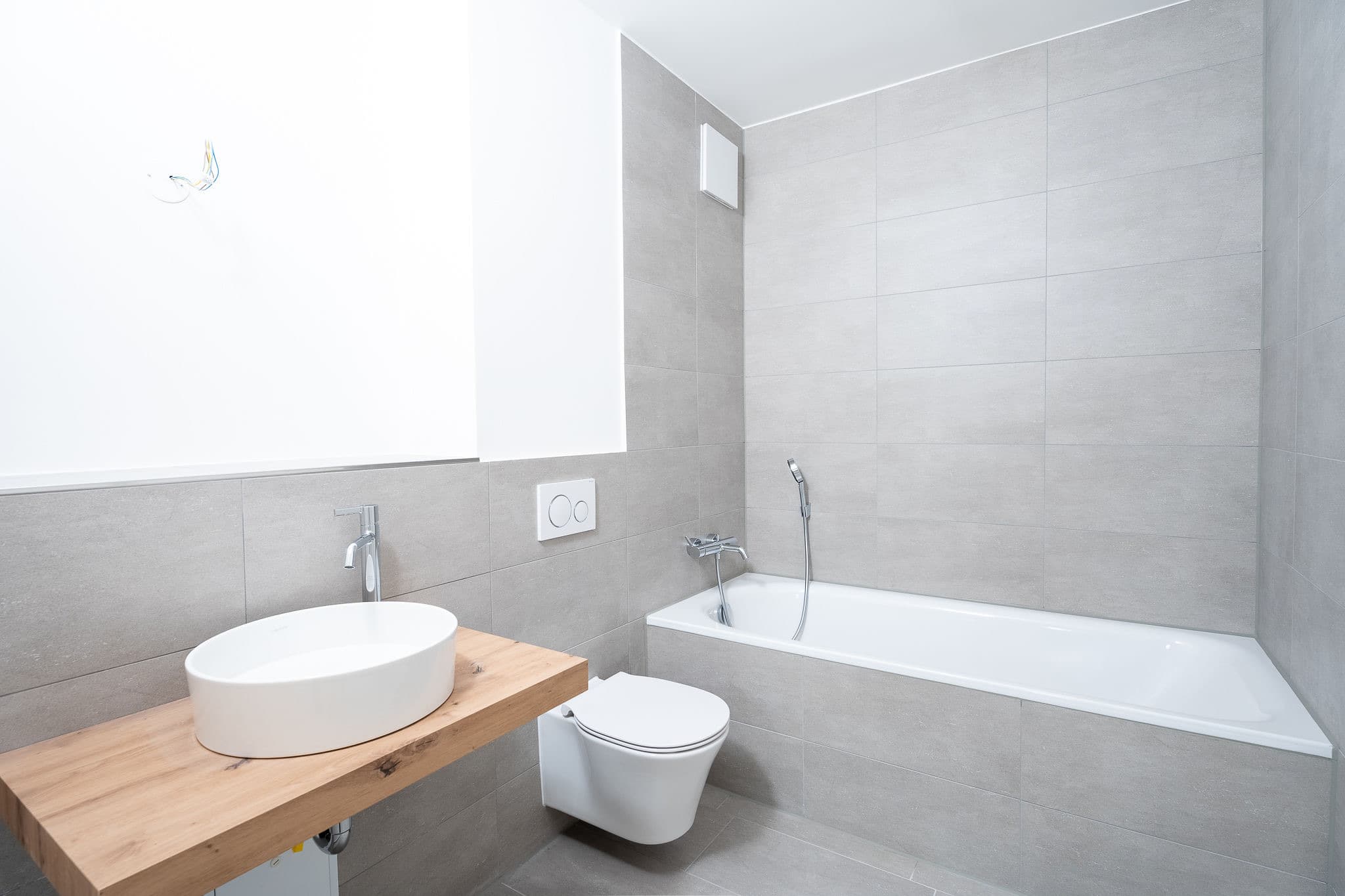 Badezimmer im Annelies Quartier mit Badewanne, wandhängendem WC und Aufsatzwaschbecken auf Holzkonsole