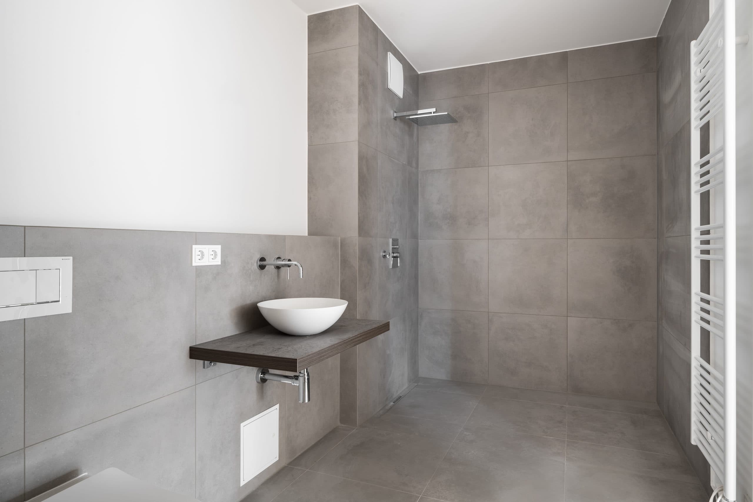 Bodengleiche, raumhoch geflieste Dusche mit Edelstahl-Duschrinne und Regenbrause