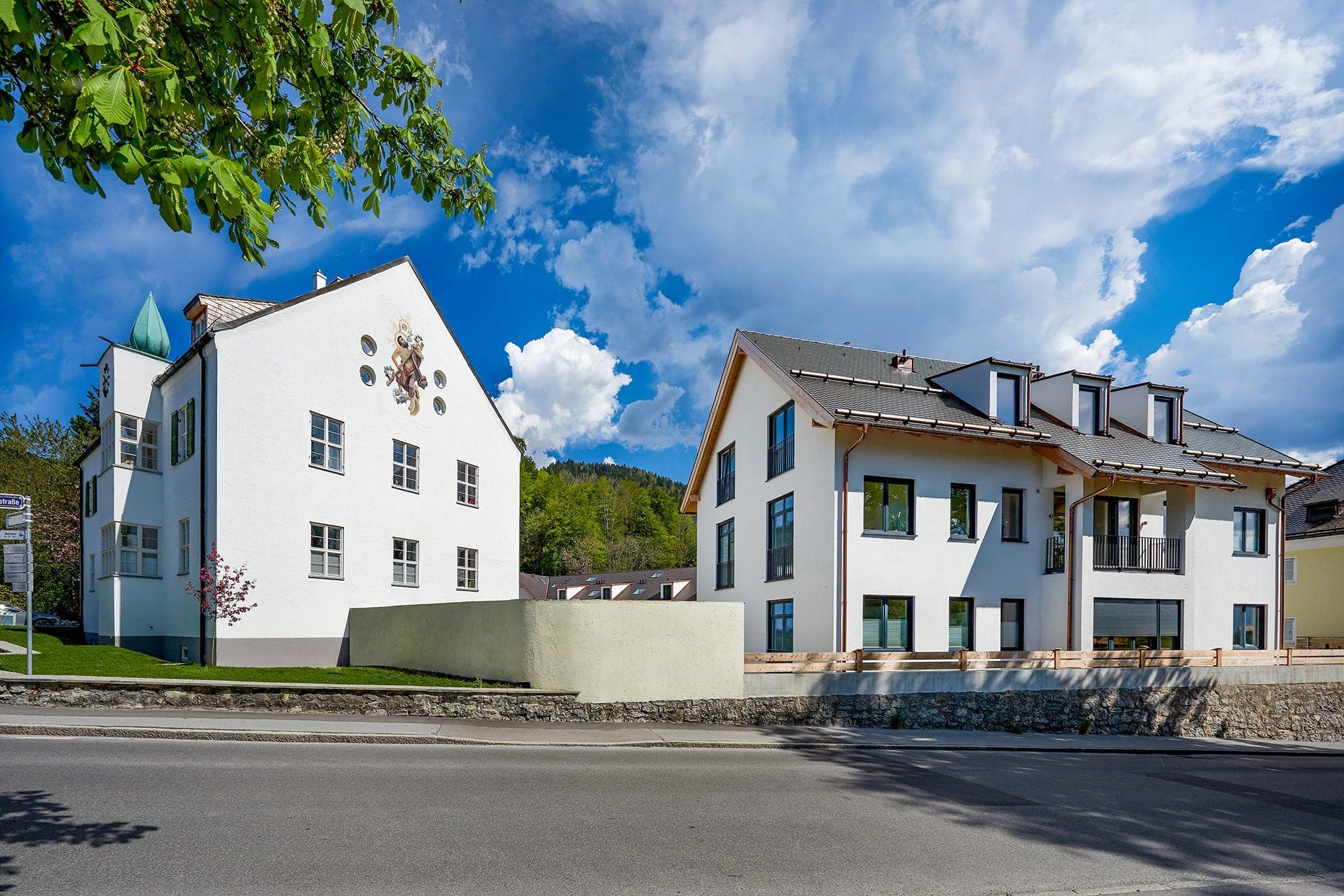 Zwei helle Wohnhäuser mit Satteldach und Malerei auf der Hausfassade
