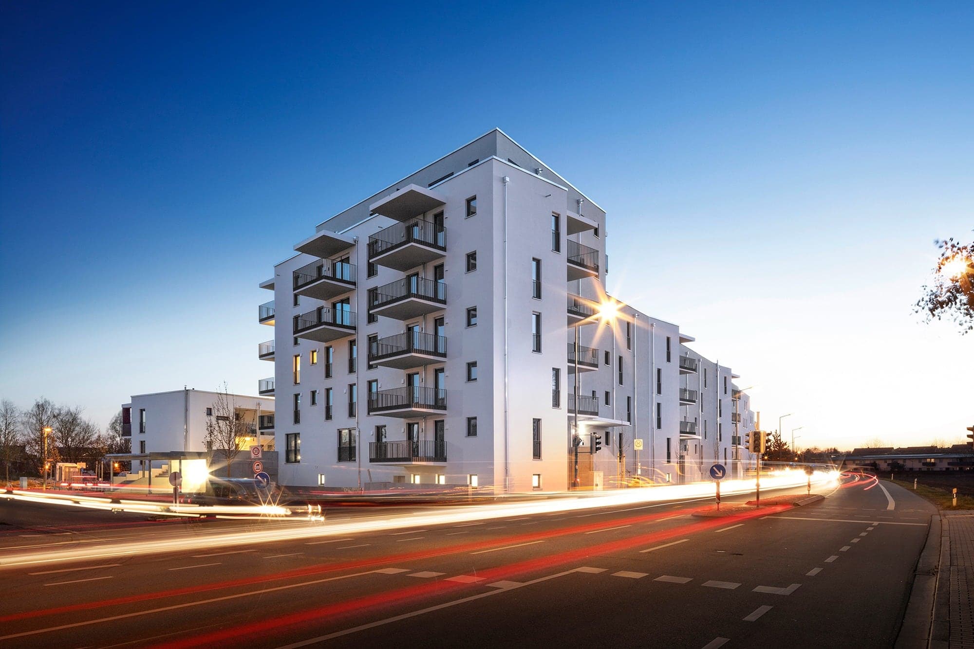 Straße und weißes, hohes Wohnhaus bei Nacht